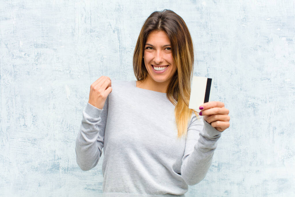 jovem mulher bonita com um cartão de crédito contra parede grunge
 - Foto, Imagem