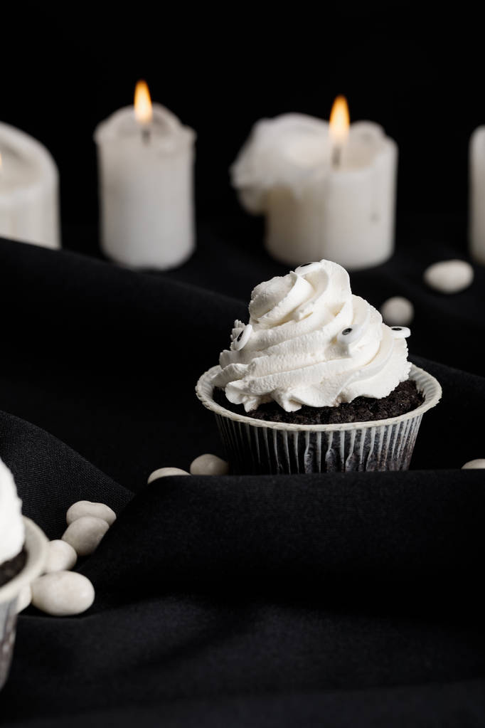 valikoiva painopiste herkullisia Halloween cupcake valkoinen kerma lähellä polttava kynttilöitä eristetty musta
 - Valokuva, kuva