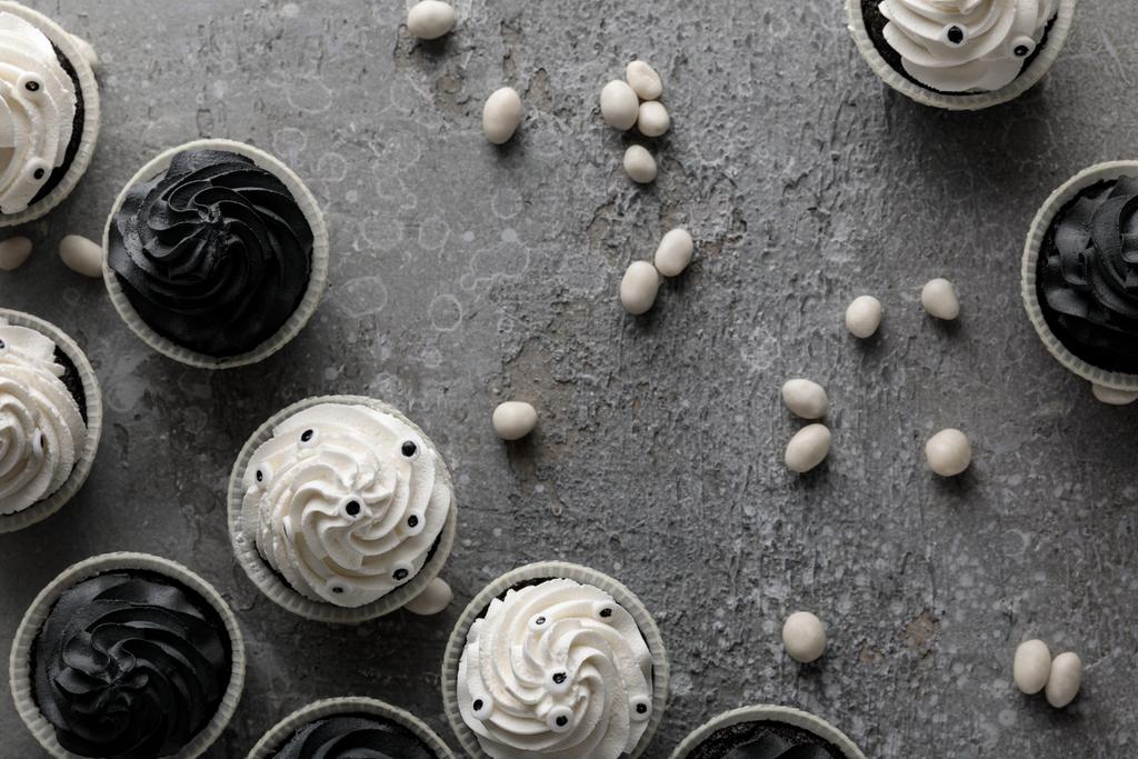 bovenaanzicht van heerlijke Halloween cupcakes en snoepjes op betonnen grijs oppervlak - Foto, afbeelding