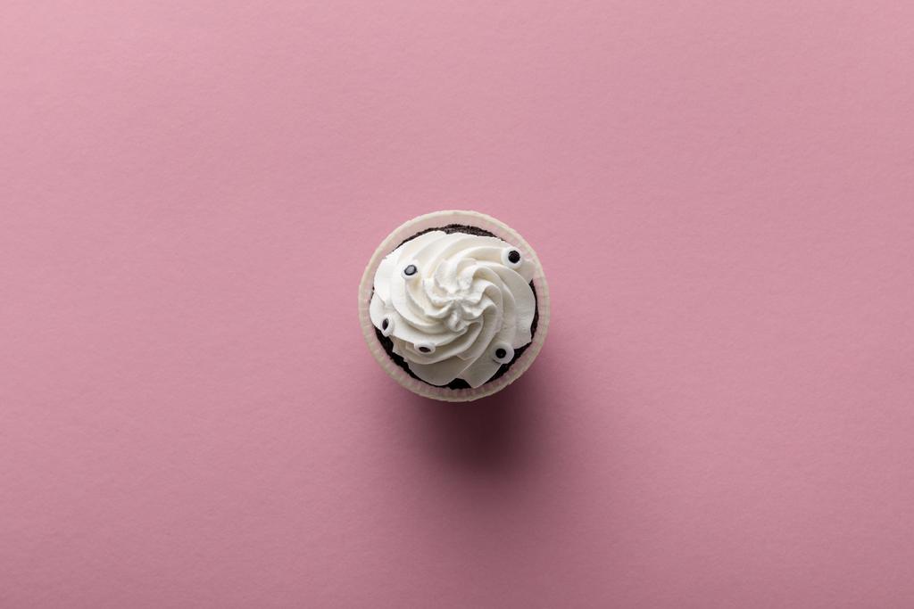 vrchní pohled na lahodný Halloween cupcake s bílým krémem na růžovém pozadí - Fotografie, Obrázek