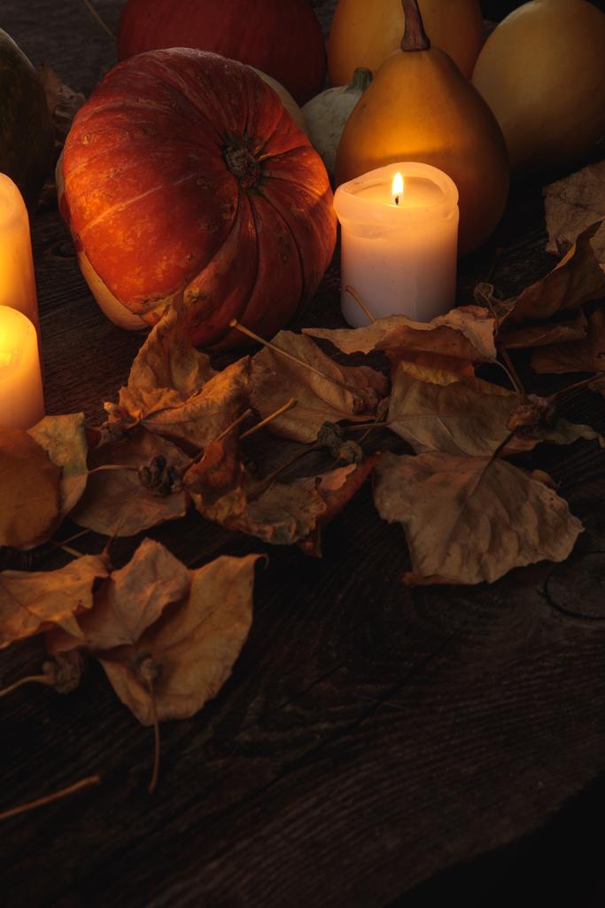 folhagem seca, velas em chamas, abóbora madura na mesa rústica de madeira
 - Foto, Imagem