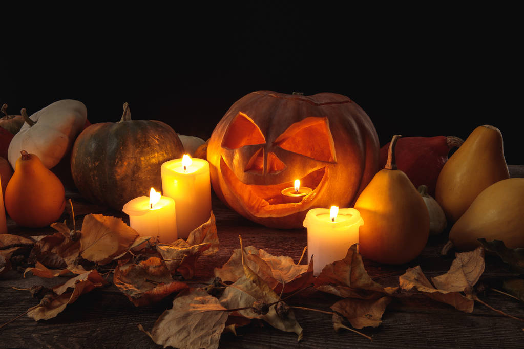 suche liście, płonące świece i wyrzeźbiona dynia Halloween na drewnianym rustykalnym stole odizolowana na czarno - Zdjęcie, obraz