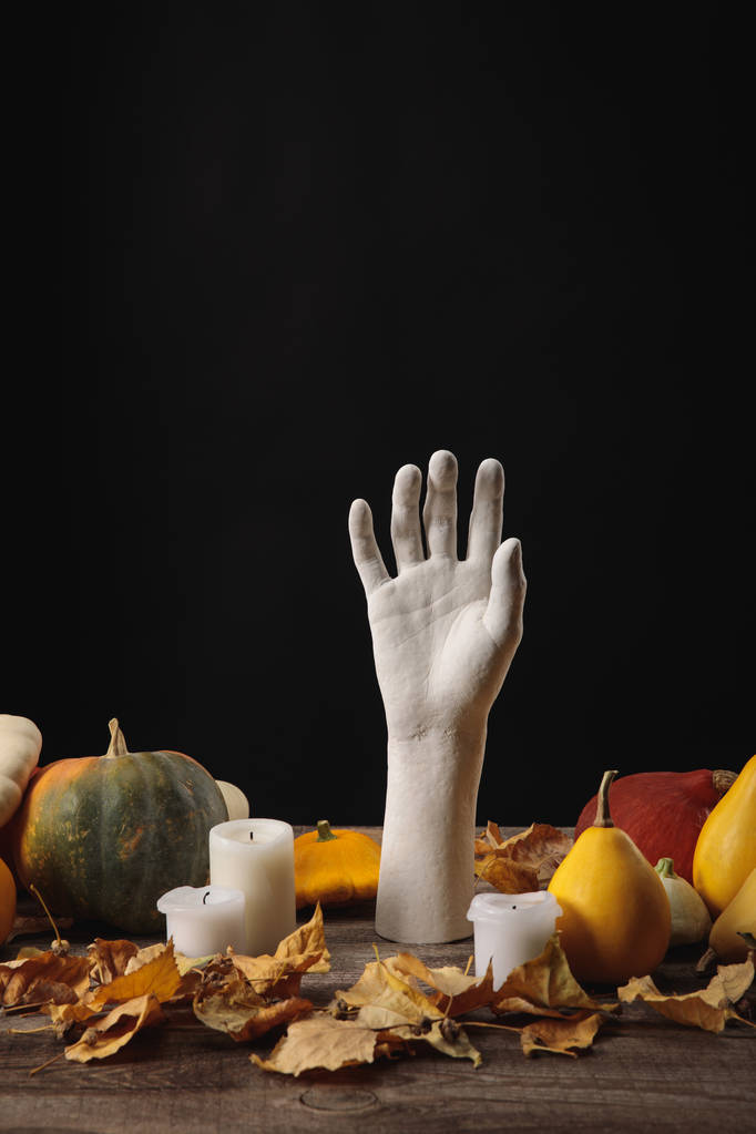 dry foliage, candles, ripe pumpkins and decorative hand on wooden rustic table isolated on black - Photo, Image