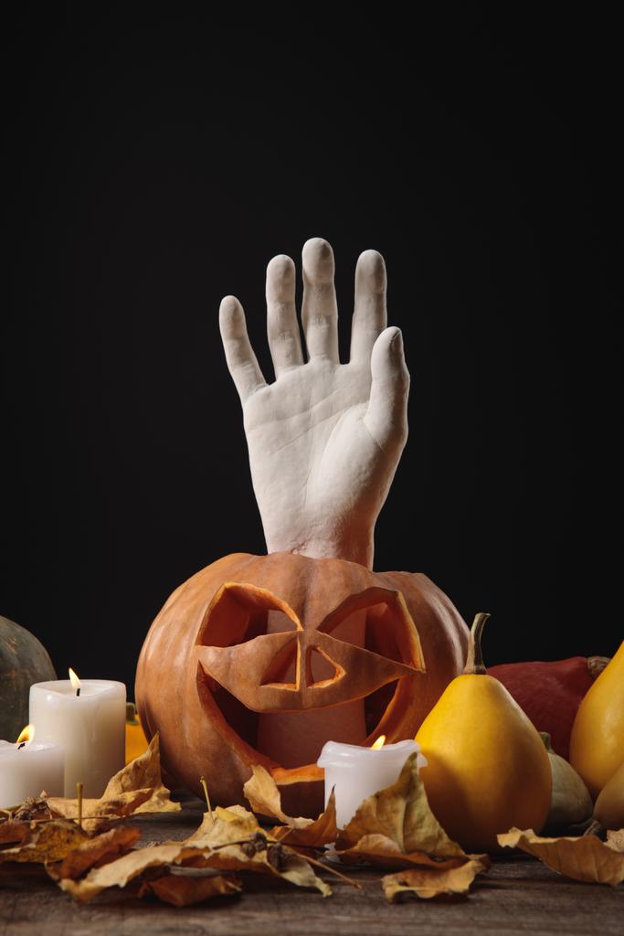 fogliame secco, candele accese, mano decorativa in zucca intagliata di Halloween su tavolo rustico in legno isolato su nero
 - Foto, immagini