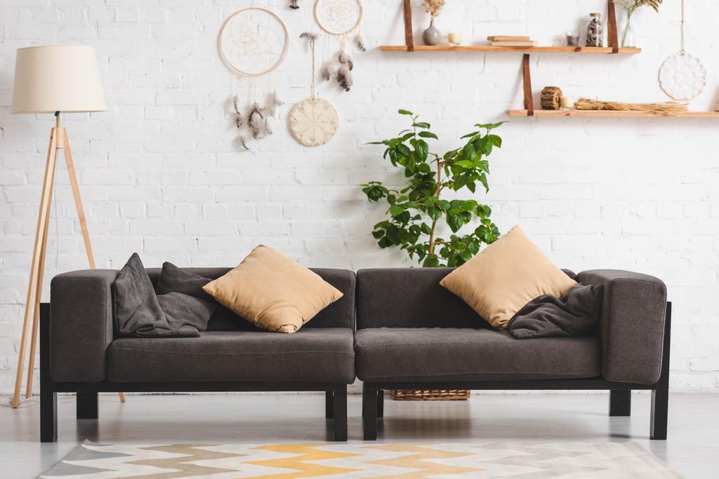 belső tér hangulatos nappali kanapéval, növényi és álomfogók téglafalon - Fotó, kép