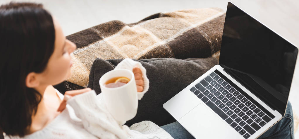 селективное внимание девушки с чашкой чая смотреть кино на ноутбуке в уютном доме
 - Фото, изображение