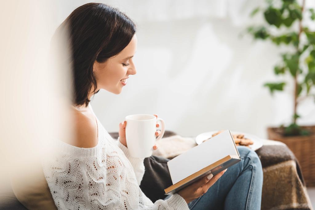 счастливая женщина читает книгу на диване с кофе и кулинарией
 - Фото, изображение