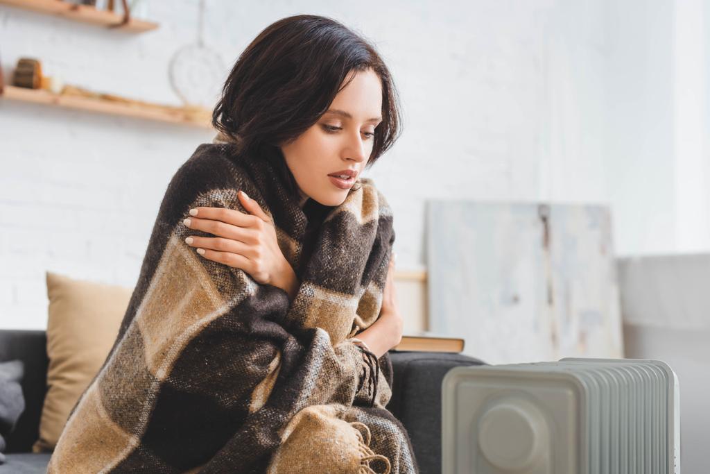 hermosa chica con manta calentando con calentador en habitación fría
 - Foto, imagen