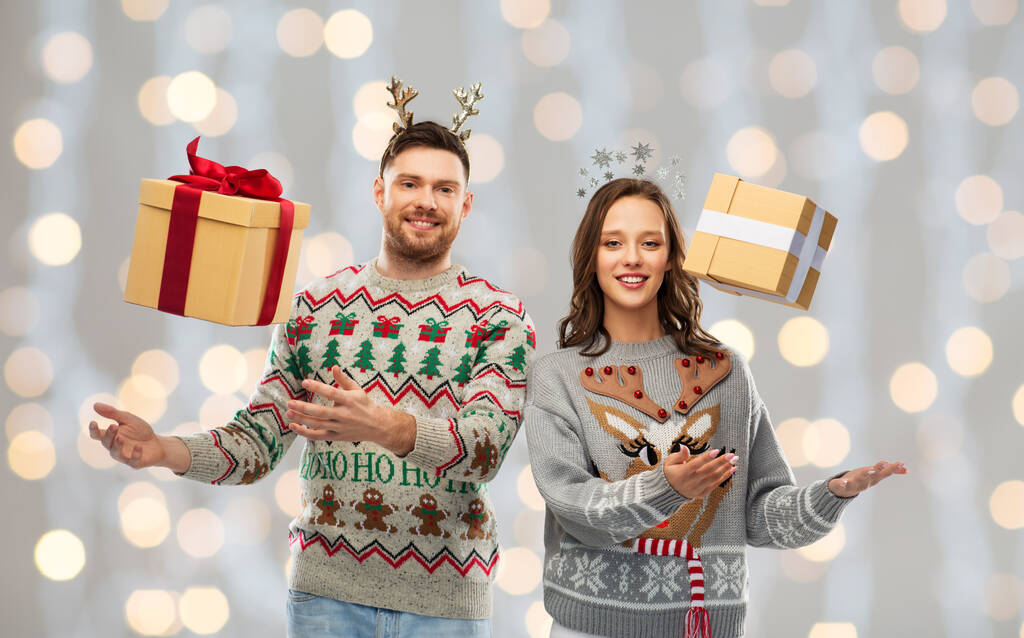 ギフトボックスとクリスマスセーターで幸せなカップル - 写真・画像