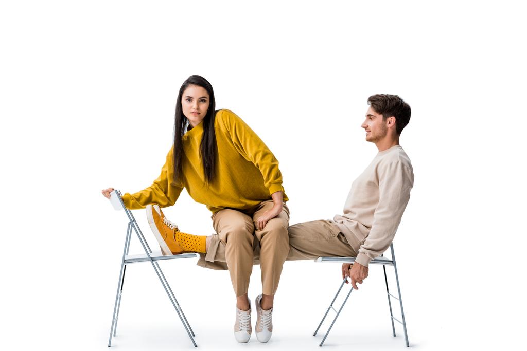 krásná dívka sedí na židli v blízkosti pohledný muž na bílém  - Fotografie, Obrázek