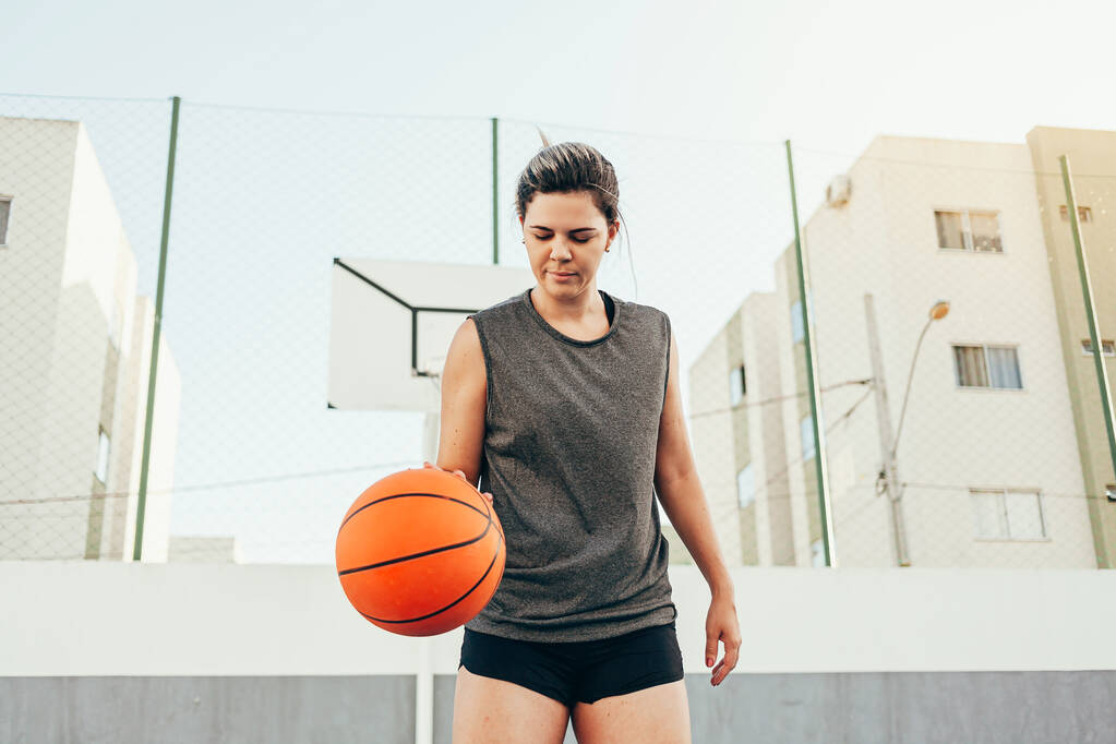mladá basketbalistka trénink venku na místním kurtu - Fotografie, Obrázek