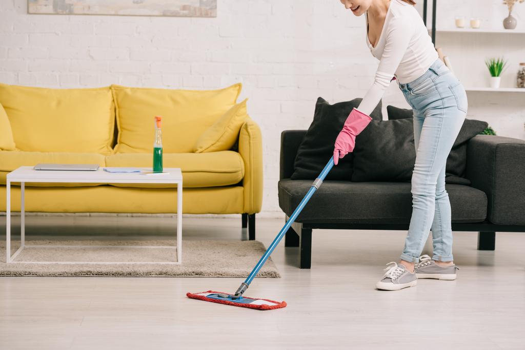 cropped view of housewife washing floor with mop near yellow and grey sofas - Photo, Image