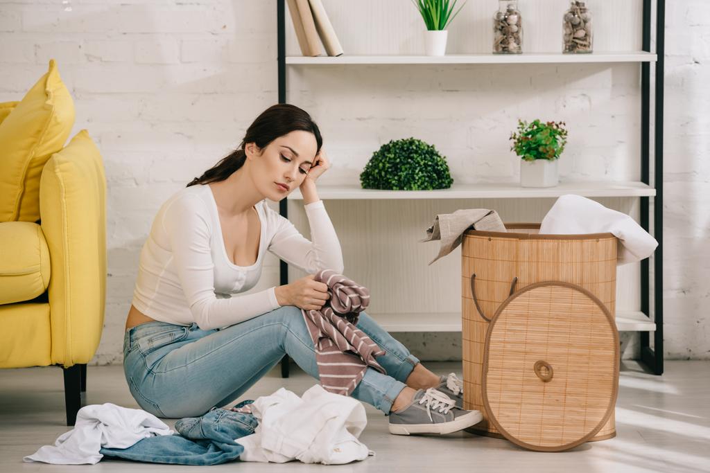 stanca casalinga seduta al piano vicino a vestiti e cesto della lavanderia
 - Foto, immagini