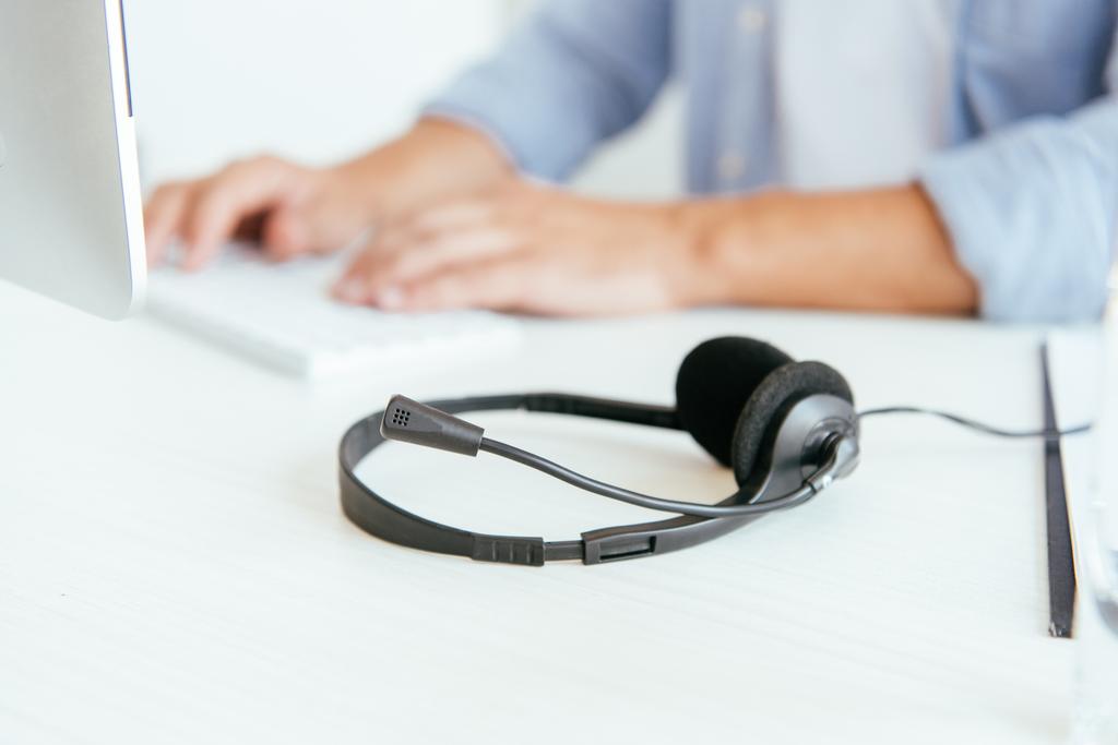 selective focus of black headset near operator in brokers agency typing in office  - Photo, Image