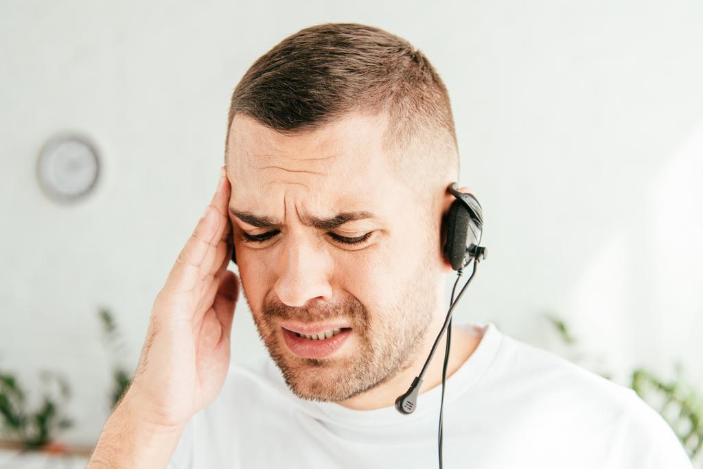 tired and upset broker touching head while working in call center  - Photo, Image