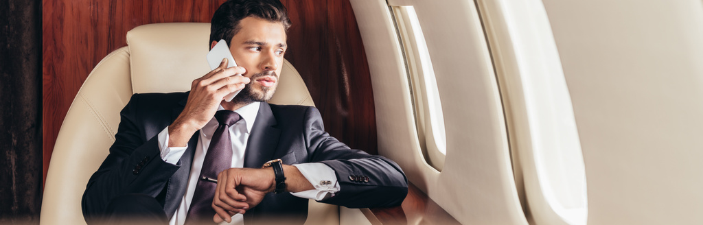 plano panorámico de hombre de negocios guapo en traje hablando en smartphone en avión privado
  - Foto, imagen