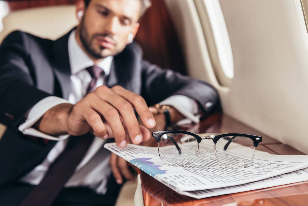 selective focus handsome businessman in suit taking glasses in private plane  - 写真・画像