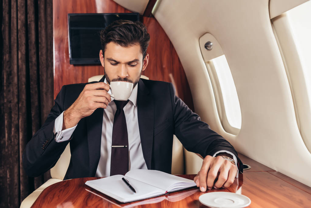 guapo hombre de negocios en traje bebiendo café en avión privado
  - Foto, imagen