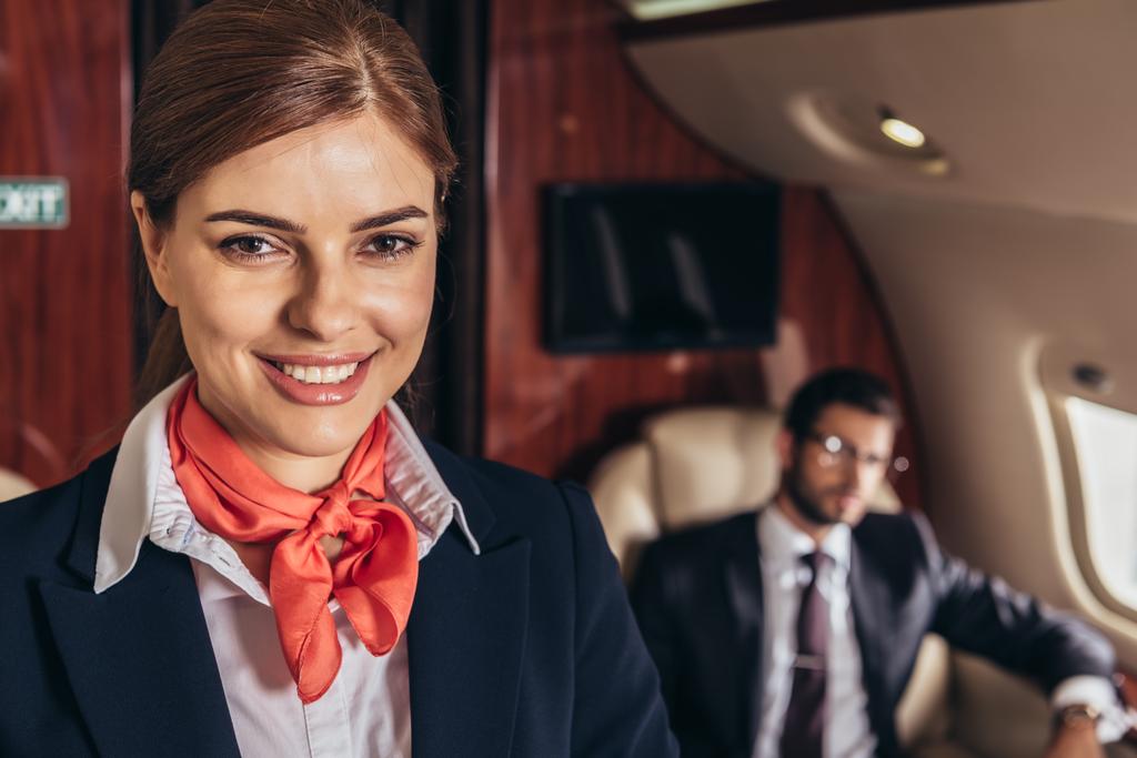 избирательный фокус улыбающейся и привлекательной стюардессы, смотрящей в камеру в частном самолете
 - Фото, изображение
