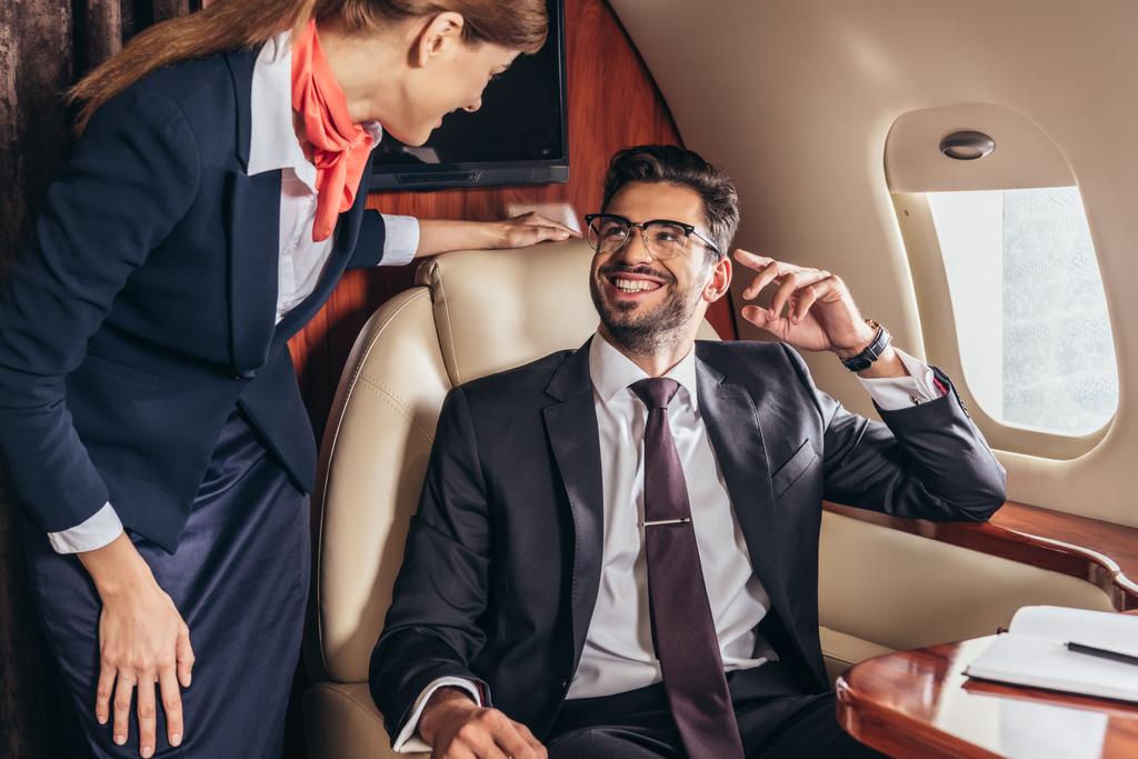 民間航空機の客室乗務員を見てスーツを着た笑顔のビジネスマン  - 写真・画像