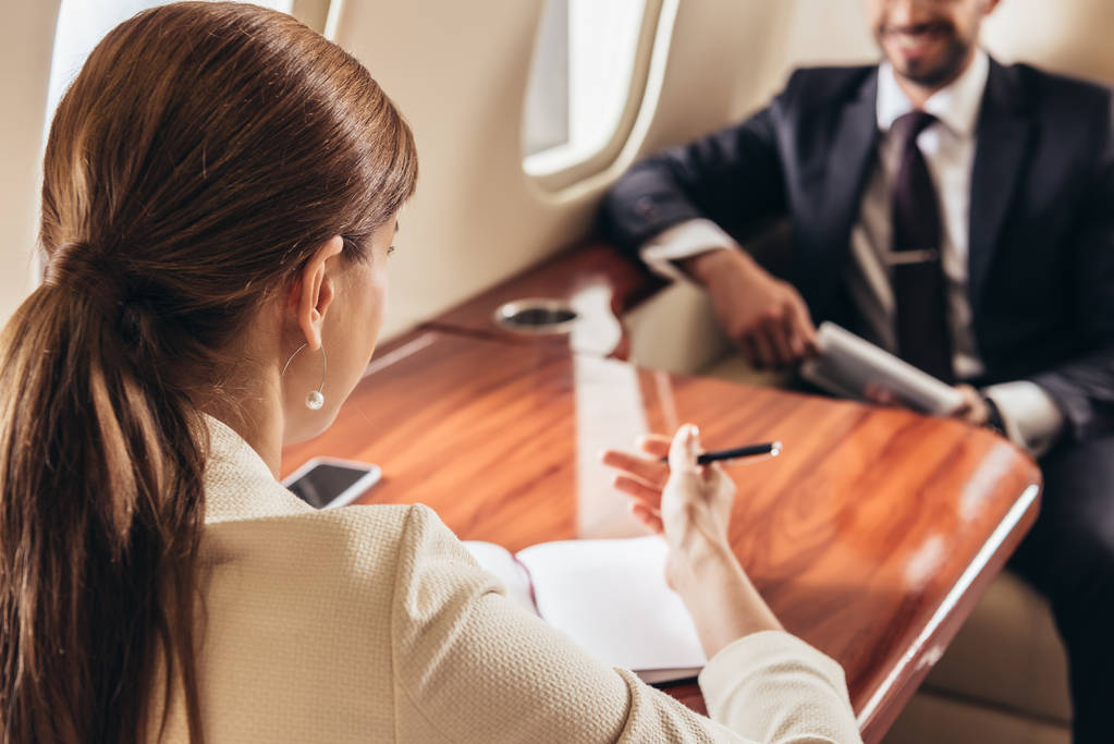 selective focus of businessman and businesswoman talking in private plane  - 写真・画像
