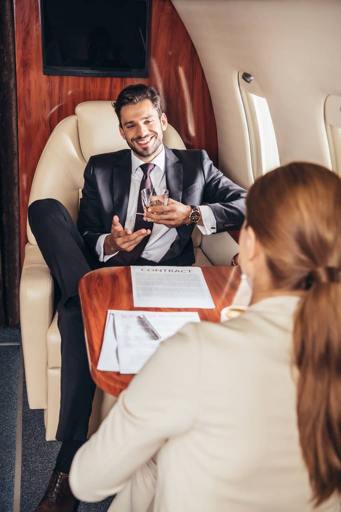 επιλεκτική εστίαση του επιχειρηματία με γυαλί μιλάμε με επιχειρηματία σε ιδιωτικό αεροπλάνο  - Φωτογραφία, εικόνα