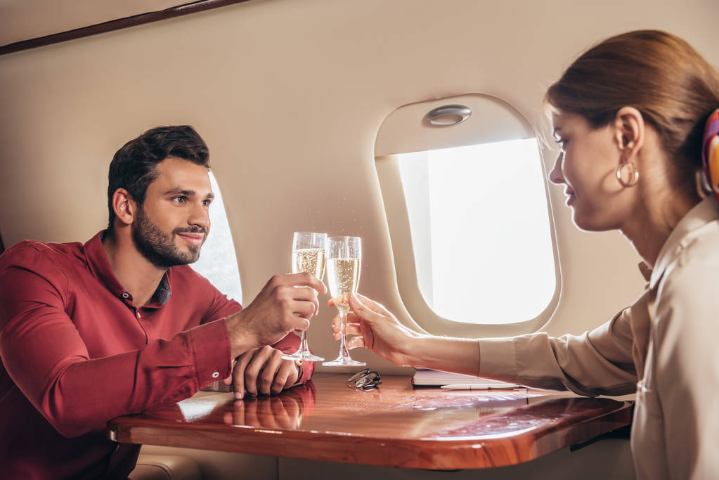 chłopak i dziewczyna brzęczenie z kieliszkami szampana w prywatnym samolocie  - Zdjęcie, obraz