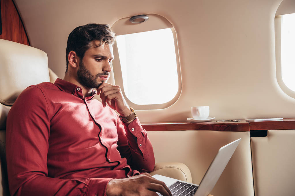 przystojny mężczyzna w koszula za pomocą laptop w prywatny samolot  - Zdjęcie, obraz