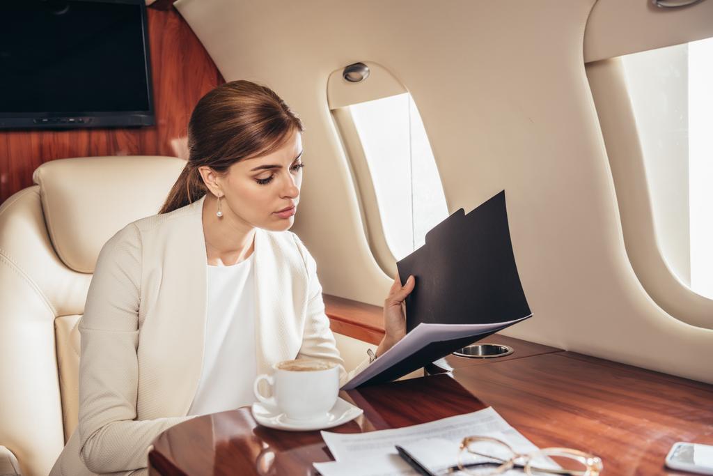ελκυστική επιχειρηματίας με κοστούμι κάνει γραφειοκρατία σε ιδιωτικό αεροπλάνο  - Φωτογραφία, εικόνα