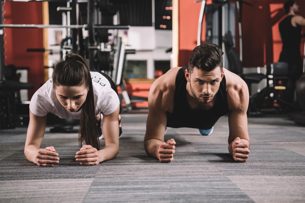 attractive trainer doing plank exercise together with handsome sportsman - Photo, Image