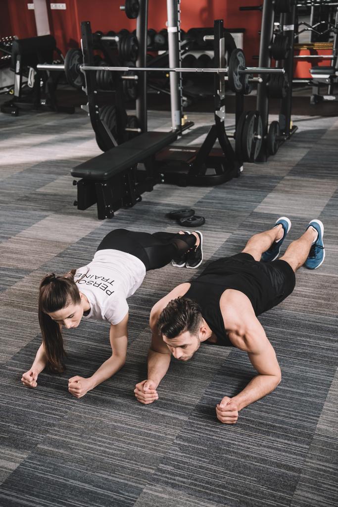 young trainer doing plank exercise together with sportsman - Photo, Image
