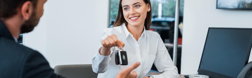 panoramatický záběr veselý auto dealer dává klíč od auta na člověka  - Fotografie, Obrázek