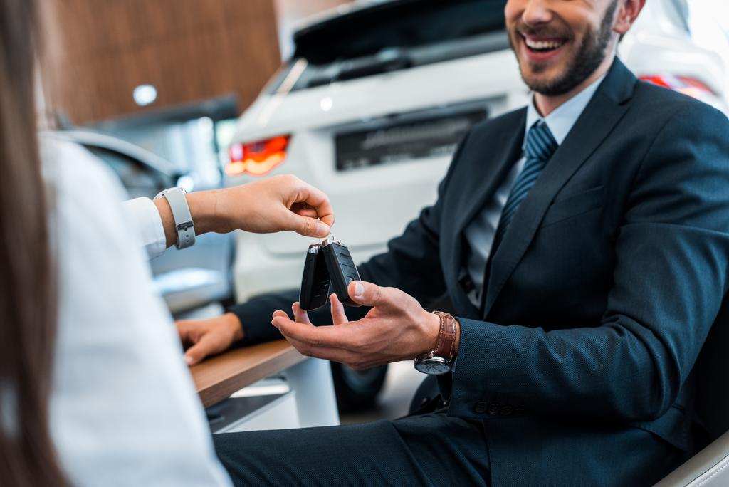cropped view of car dealer giving car keys to happy bearded man  - Photo, Image