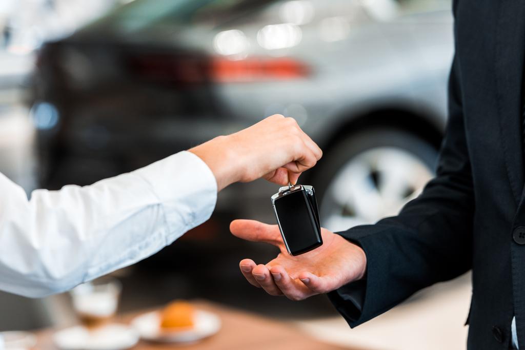 bijgesneden weergave van auto dealer geven autosleutel aan de mens  - Foto, afbeelding