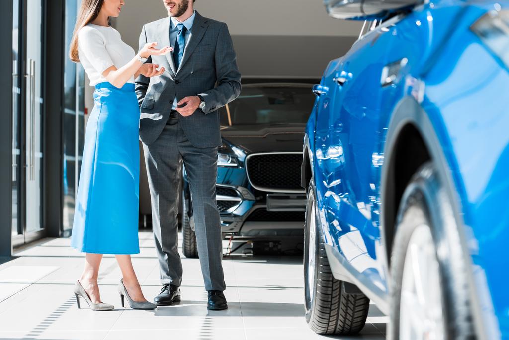 обрізаний вид жінки жестикулює, стоячи біля бородатого чоловіка і автомобілів
  - Фото, зображення