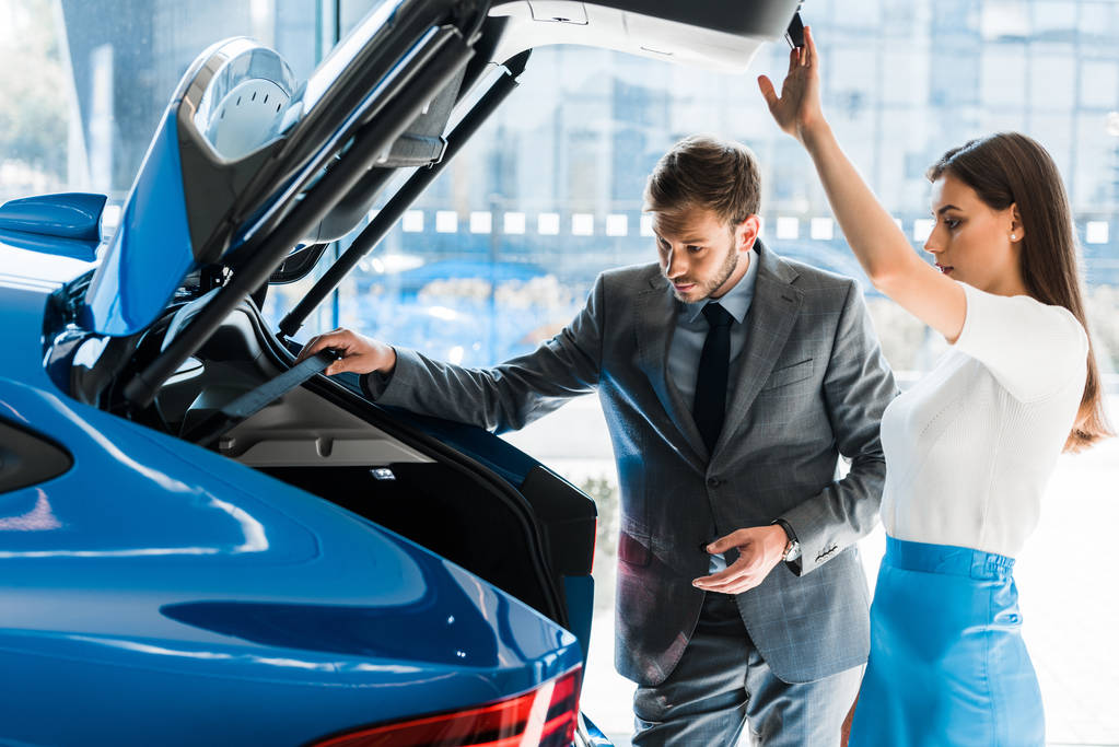 valikoiva painopiste houkutteleva nainen ja komea mies etsii auton runko auton showroom
  - Valokuva, kuva