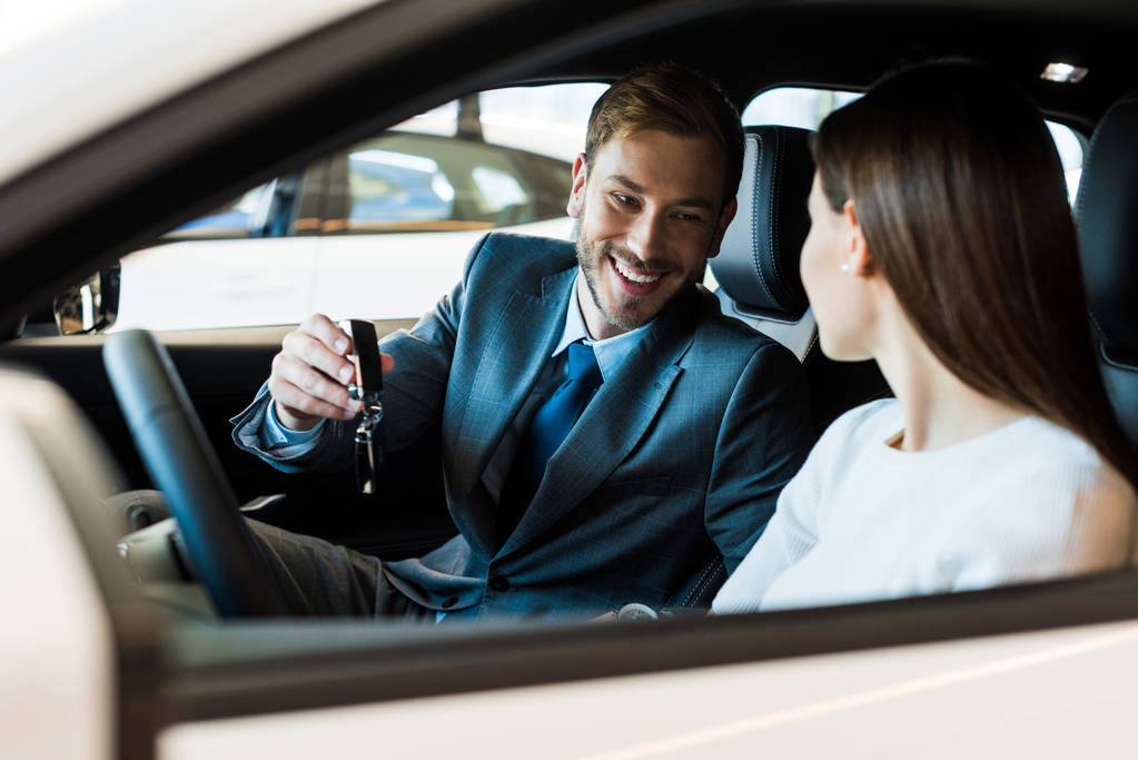 selektivní zaměření šťastný vousatý muž držící klíč od auta v blízkosti ženy  - Fotografie, Obrázek