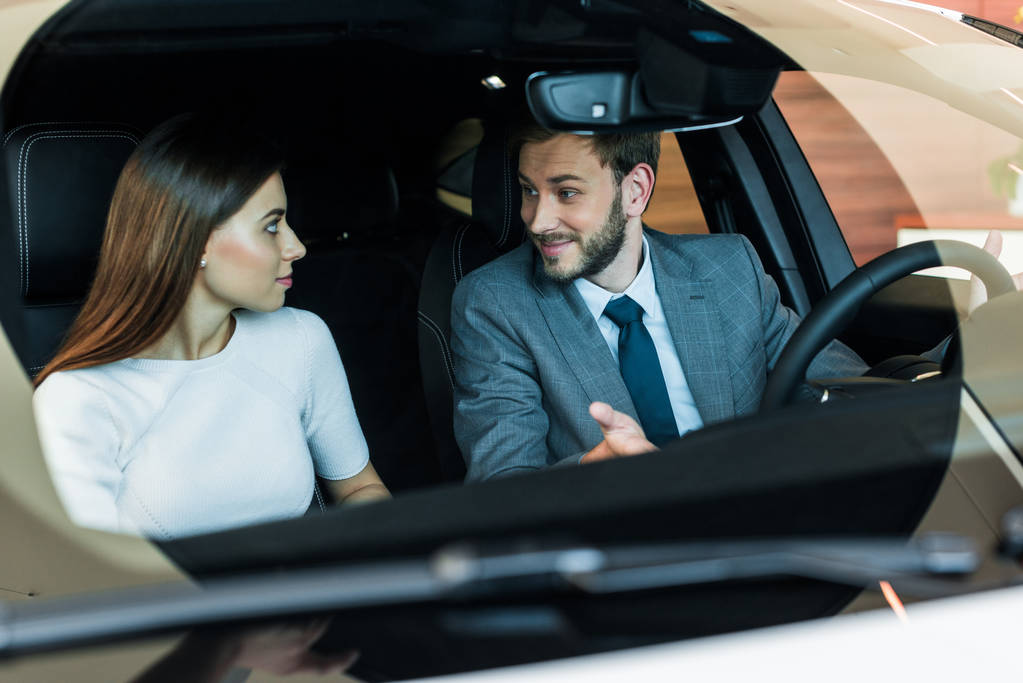 επιλεκτική εστίαση του γενειοφόρου άνδρα κοιτάζοντας τη γυναίκα στο αυτοκίνητο  - Φωτογραφία, εικόνα