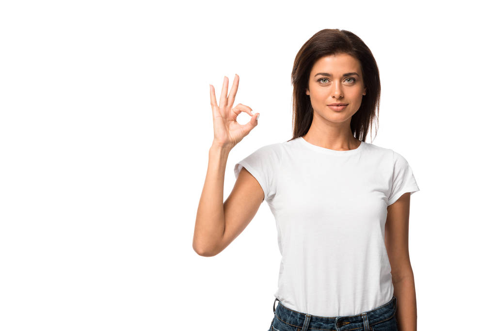 chica atractiva en camiseta blanca que muestra signo ok, aislado en blanco
 - Foto, imagen