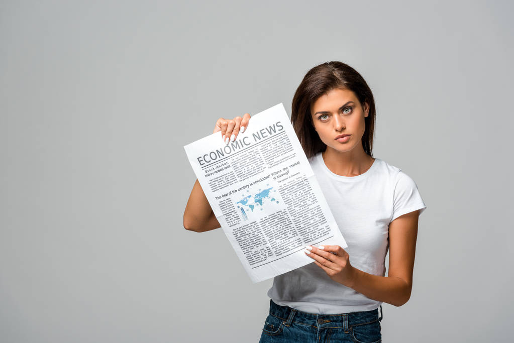 grave jovem mostrando jornal econômico, isolado em cinza
 - Foto, Imagem
