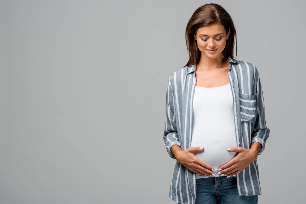 schöne glückliche schwangere Frau berührt Bauch isoliert auf grau - Foto, Bild