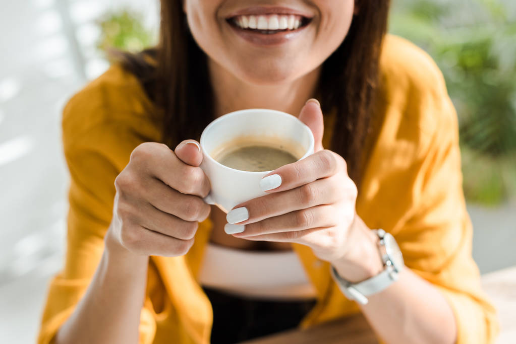 visão cortada de freelancer sorrindo segurando xícara de café no escritório em casa
 - Foto, Imagem