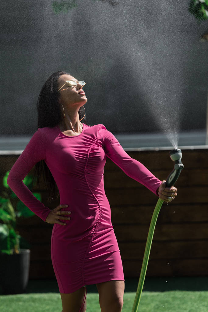 vonzó nő ruha és napszemüveg pózol víztömlő kívül  - Fotó, kép