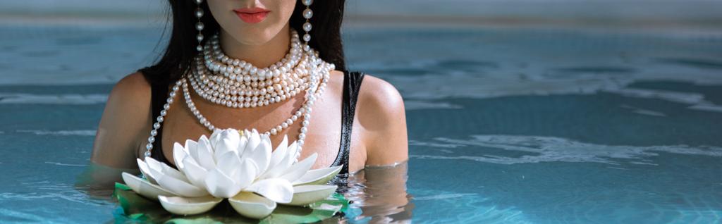 Panoramaaufnahme einer Frau in schwarzem Badeanzug und Perlenkette, die im Pool posiert  - Foto, Bild