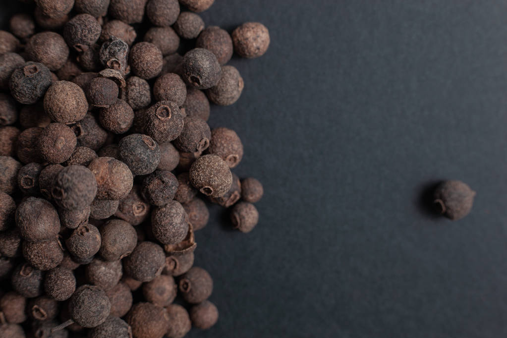 Spice allspice black peppercorns scattered on a black background - Photo, Image