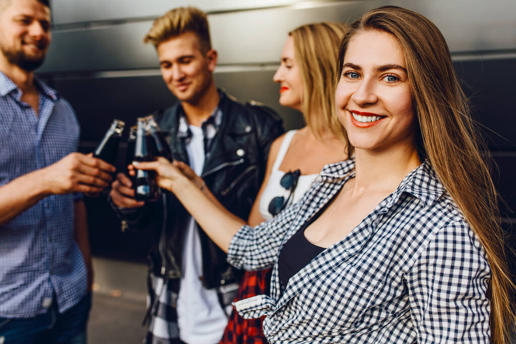 Группа друзей, девушек и парней гуляют по городу вместе у черной стены, веселятся и пьют напитки
 - Фото, изображение