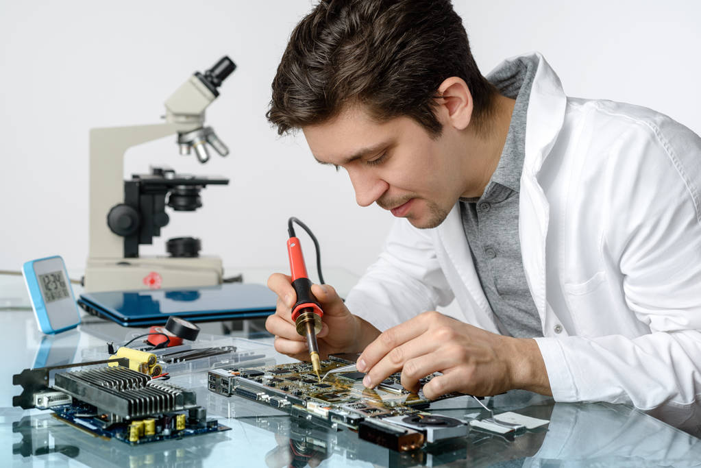 Молодий енергійний чоловічий технік або інженер ремонтує електронне обладнання
 - Фото, зображення