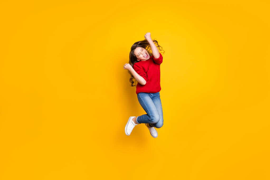 Full size photo of delighted crazy child wavy curly hair lucky kid win contest raise fists scream yeah wear stylish trendy pullover white sneakers isolated over yellow color background - Photo, Image