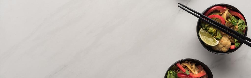 вид зверху смачна гостра тайська локшина з паличками на мармуровій сірій поверхні, панорамний знімок
 - Фото, зображення