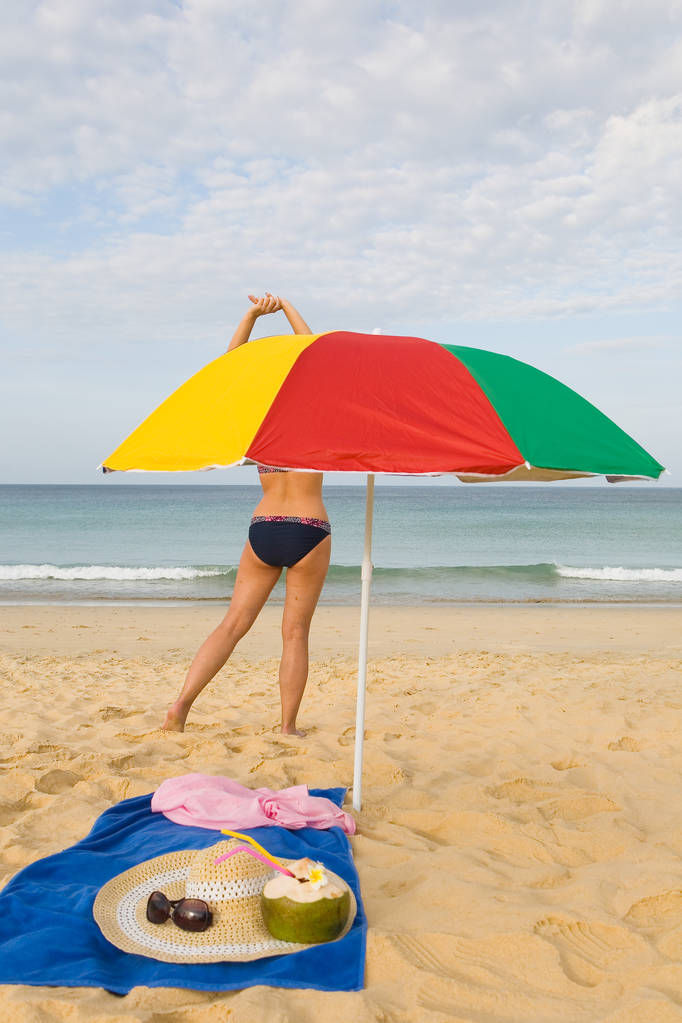 Na costa de uma praia arenosa abaixo de um guarda-chuva estão óculos de sol
, - Foto, Imagem